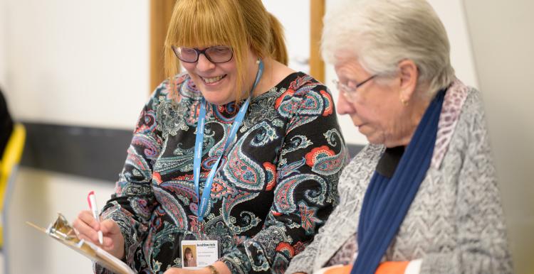 A Healthwatch worker helping an older woman complete a form