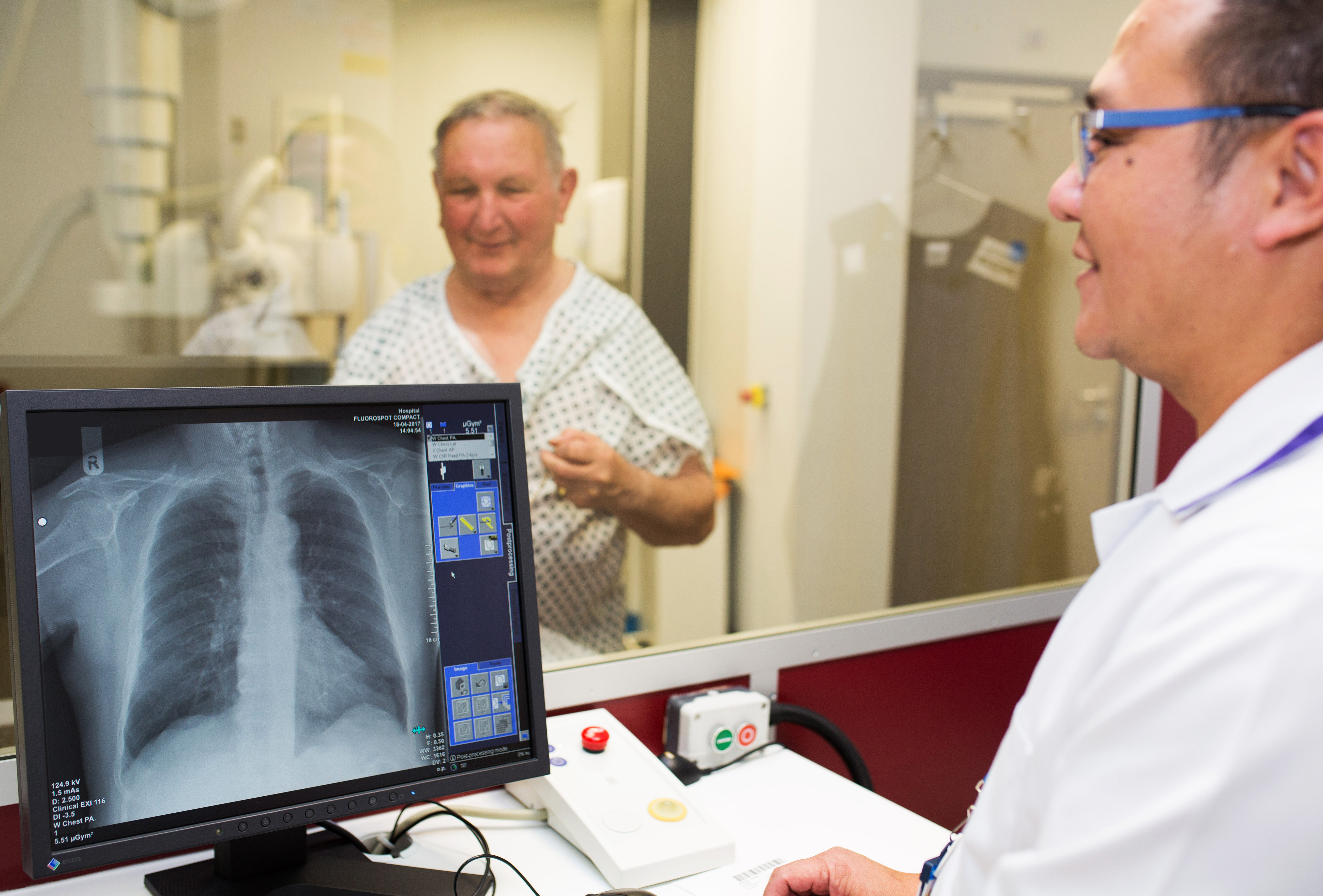 Man having xray, in the foreground you can see the x-ray technician and a picture of the person's chest x-ray