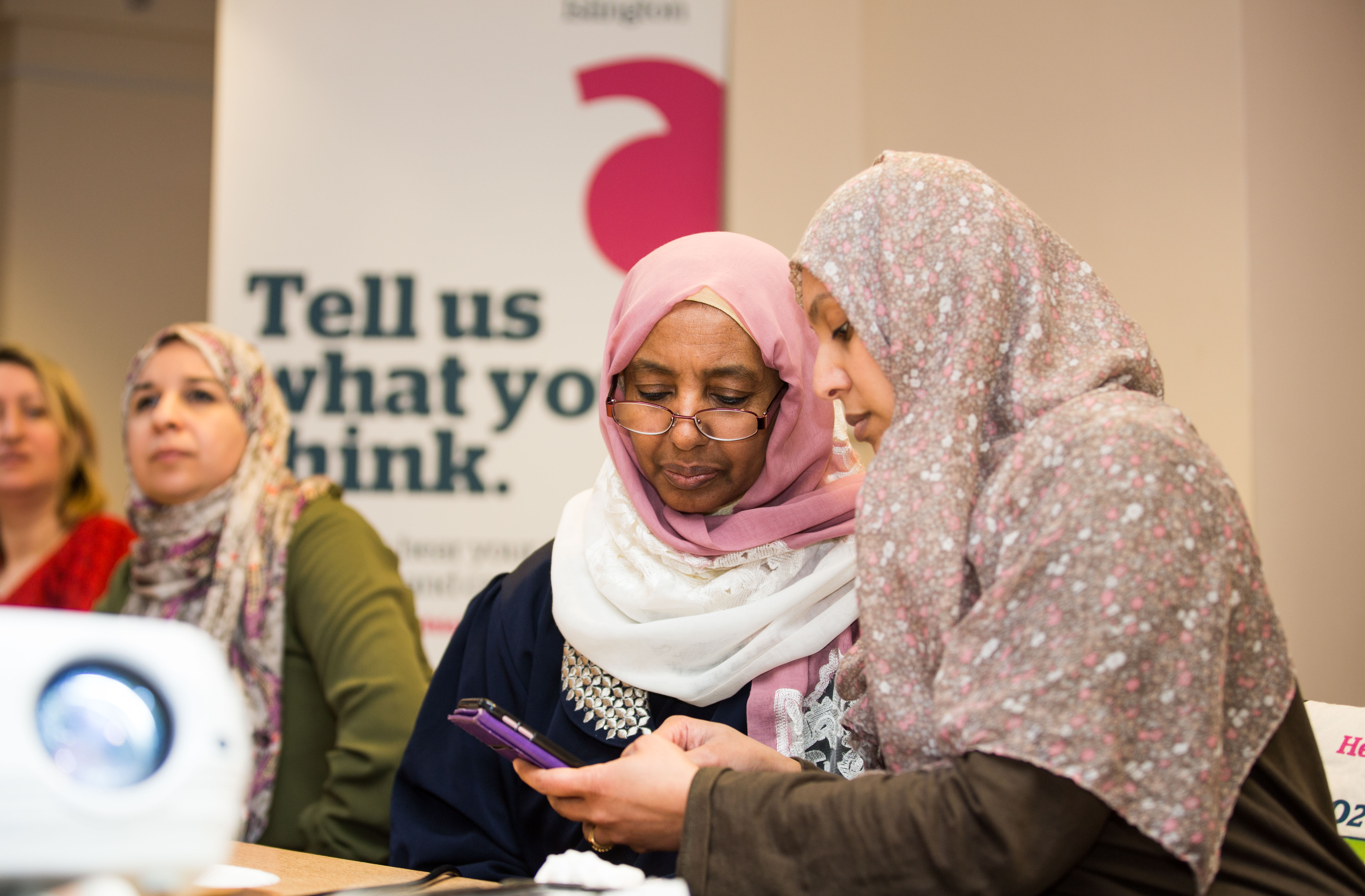Two women at a Healthwatch event looking at a mobile phone 