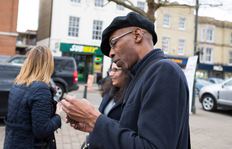 Man looking at phone as he walks in the street 