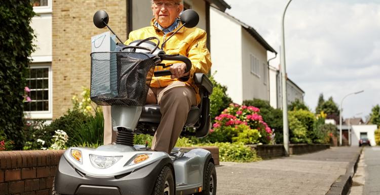 A man using a mobility scooter on a pavement