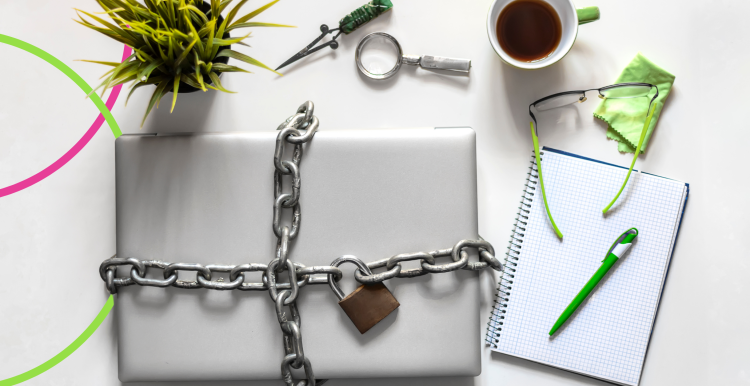 A laptop chained and locked up on a desk next to a plant, coffee cup and a pen and paper. Healthwatch Cambridgeshire and Peterborough logos in the bottom lefthand corner. 