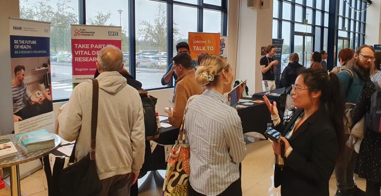 Delegates gather at the Summit event. People are talking to each other or visiting stands in the background.