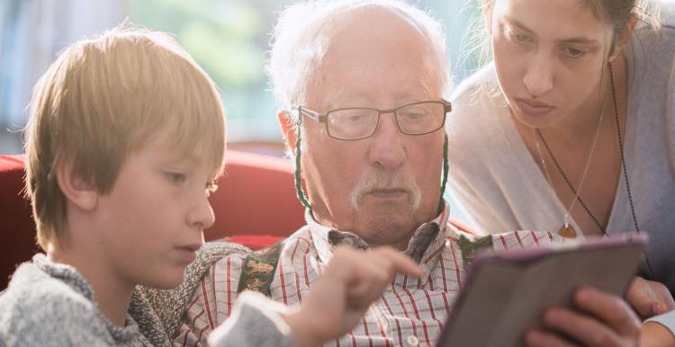 Children and an older person using an electronic tablet device