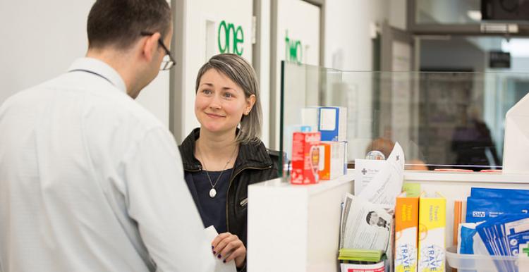 Woman picking up a prescription at chemist's