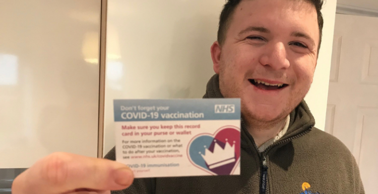 young man holding Covid-19 vaccination card 
