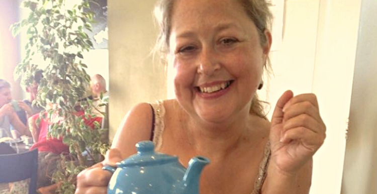 woman smiling at camera with tea pot in her hand