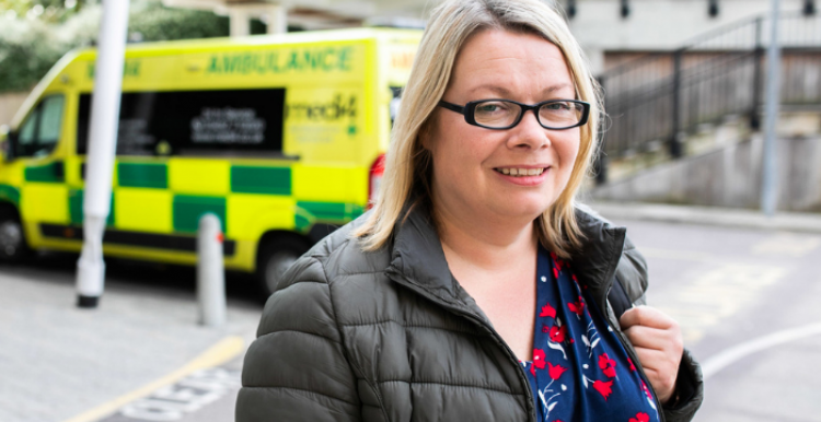 woman at hospital with ambulance in background