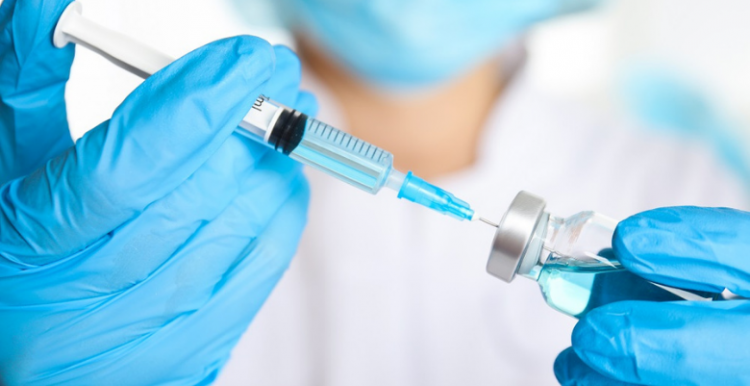 A doctor fills a vaccine syringe