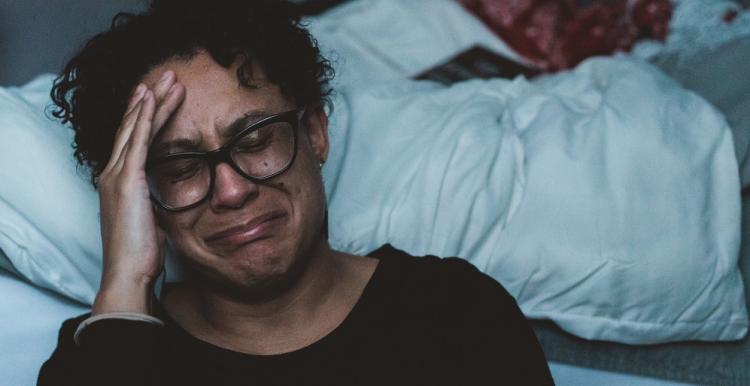 woman crying next to a bed