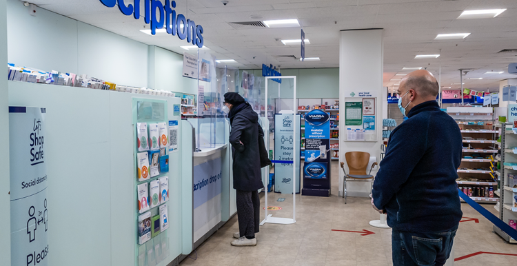 People queuing in a pharmacy to collect prescriptions