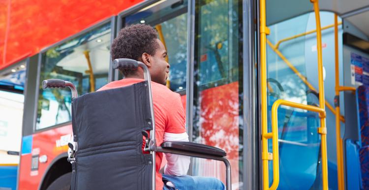 man in wheelchair waiting to board a bus