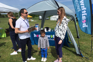 Healthwatch team member Rebwar talking to a mother and child in Ferry Meadows, Peterborough
