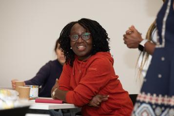 A woman sat at a table in a room with other people