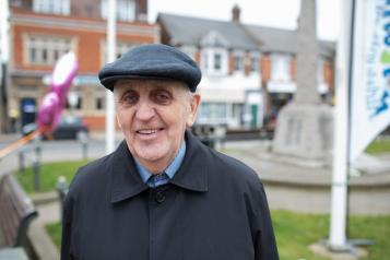 An elderly man wearing a hat smiling at the camera