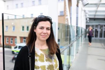 Woman outside hospital building looking at camera 