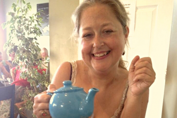 woman smiling at camera with tea pot in her hand