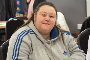 Young woman sat indoors looks at camera 