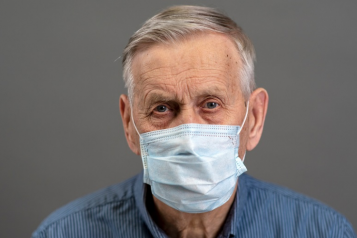 Older man in mask looking at camera