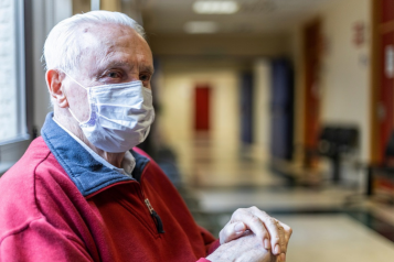 Older man wearing a face covering in hospital