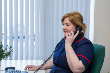 Nurse at palliative care hub taking a call on a landline 