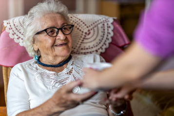 elderly woman at a care home welcomes a visitor