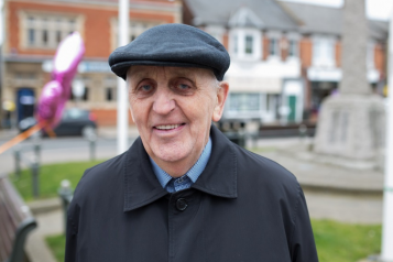 older man in a flat cap smiling at camera