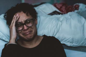 woman crying next to a bed