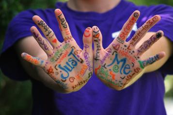 Picture shows words and designs painted on young person's hand 