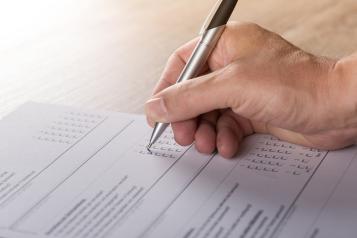 Person's hand completing a questionnaire 