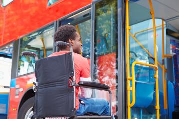 man in wheelchair waiting to board a bus