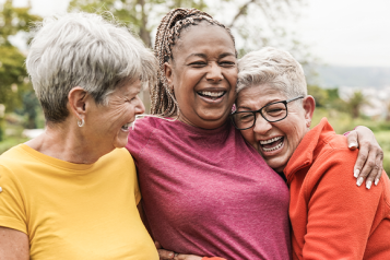 Three women outdoors, laughing and hugging