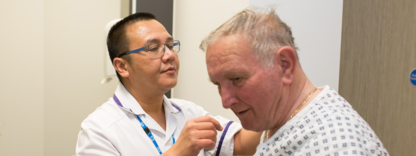 Older man in hospital gown with radiographer 