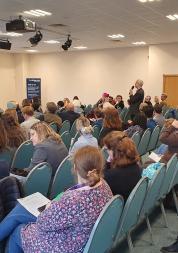 A member of the audience puts a question to a panel of experts at our Summit event. Audience members are watching.