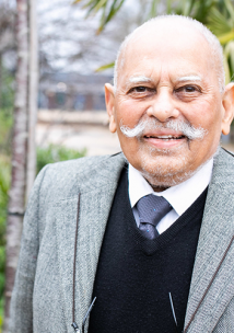 Picture shows older man of South Asian origin looking at the camera 